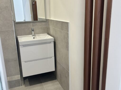 Kúpeľňa so závesnou skrinkou pod umývadlom, sivým obkladom a medeným rúrkovým radiátorom Rekonštrukcia kúpeľne v Novom Meste, Bratislava: závesná skrinka pod umývadlom a medený rúrkový radiátor