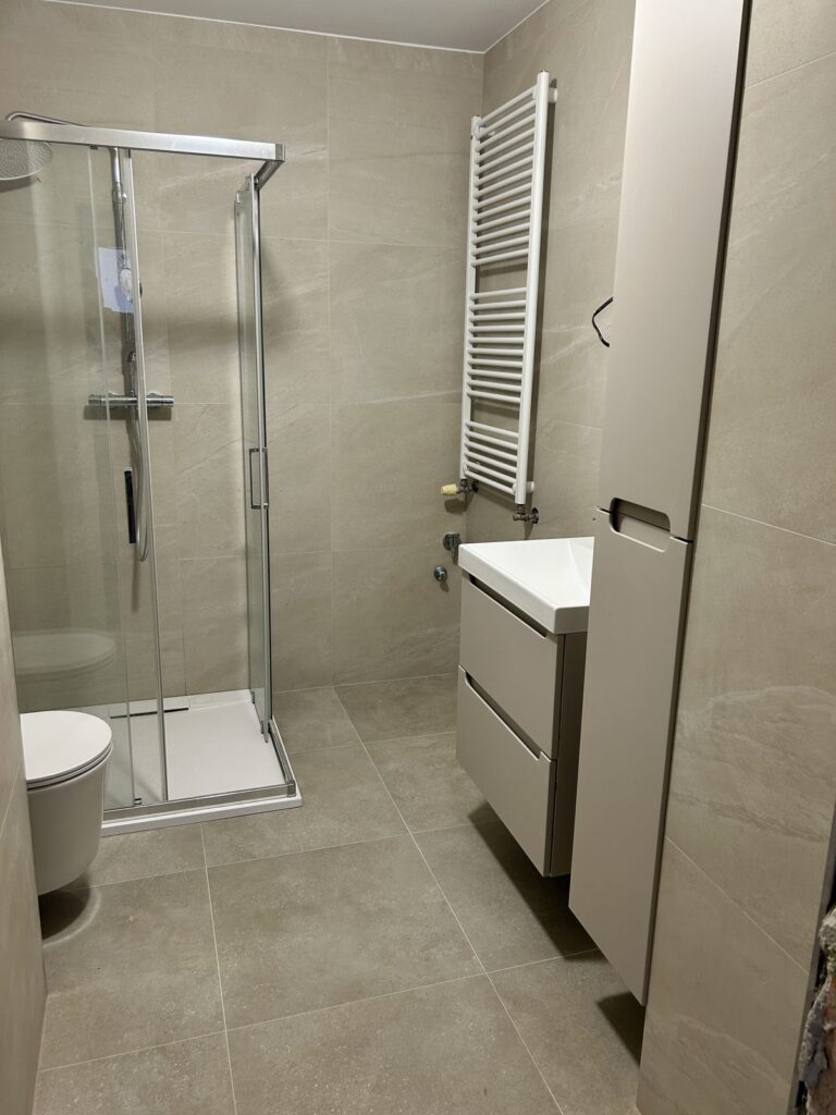 Rekonštrukcia kúpeľne v Ružinove, Bratislava: sprchový kút, závesná skrinka pod umývadlom a vysoká skrinka