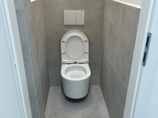 Samostatné WC so závesnou misou, sivým obkladom a LED podsvietením nad obkladom Rekonštrukcia WC v Novom Meste, Bratislava: závesná misa a LED podsvietenie nad obkladom